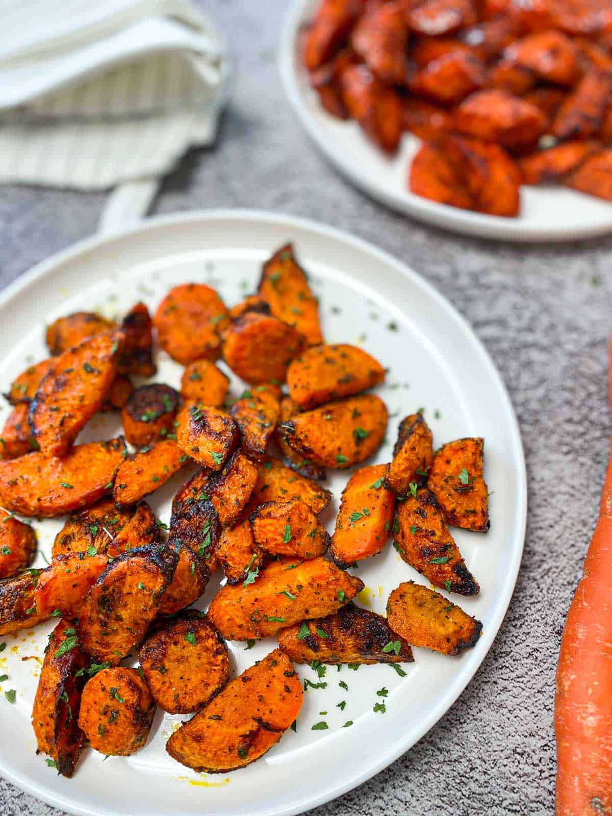 spicy air fried carrots in white serving plate with parsley sprinkled on top