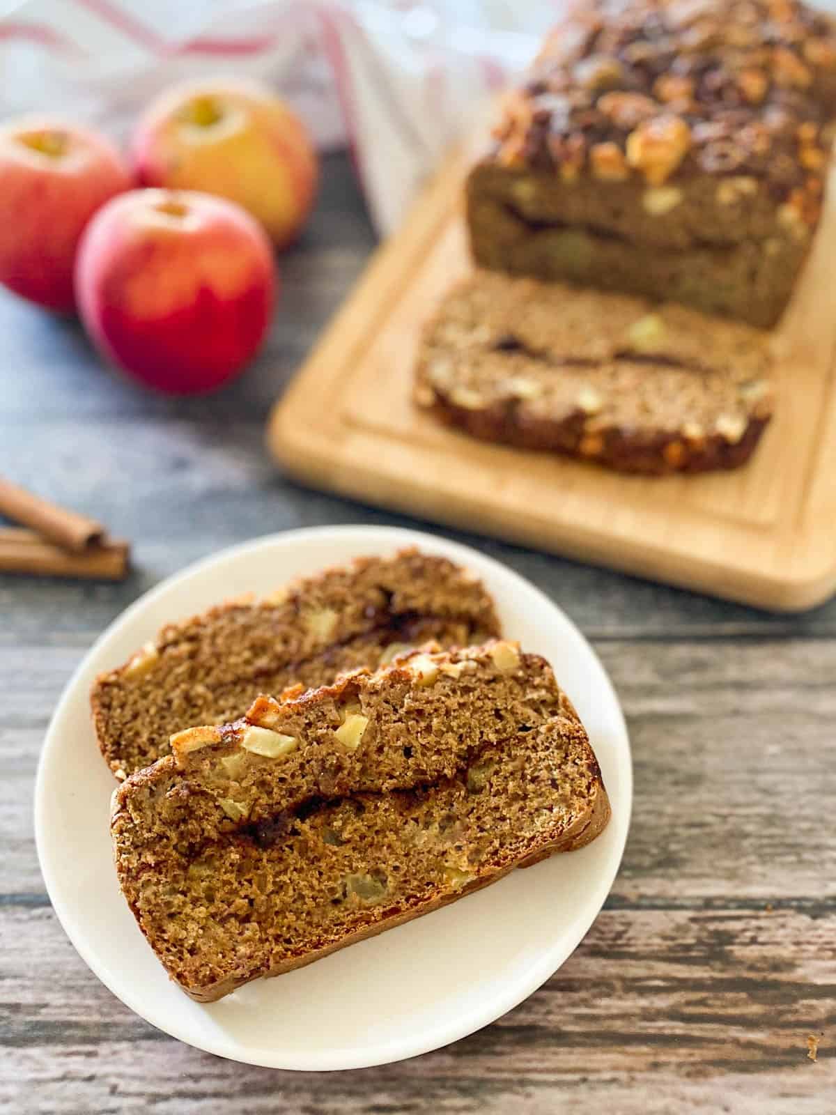 vegan apple loaf sliced on a white plate with cinnamon swirl in the center of each slice.
