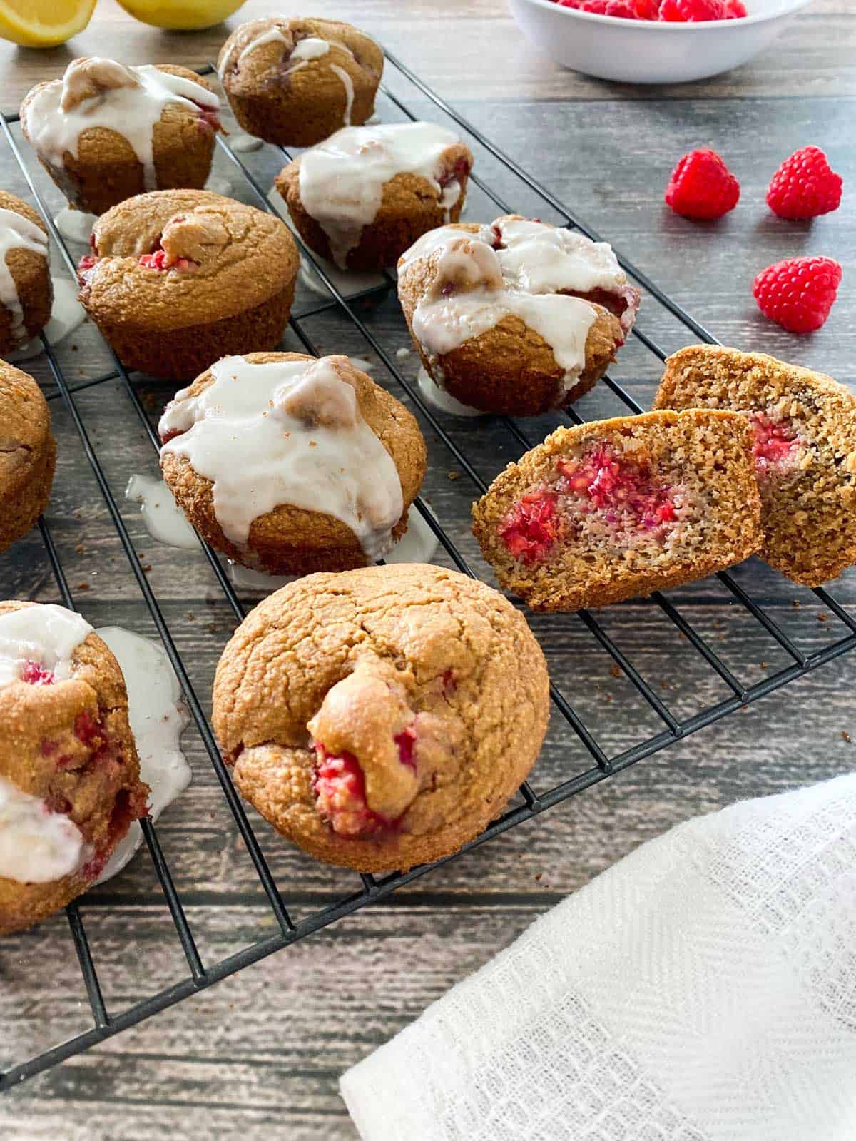 raspberry muffin cut in half on cooling rack with other muffins
