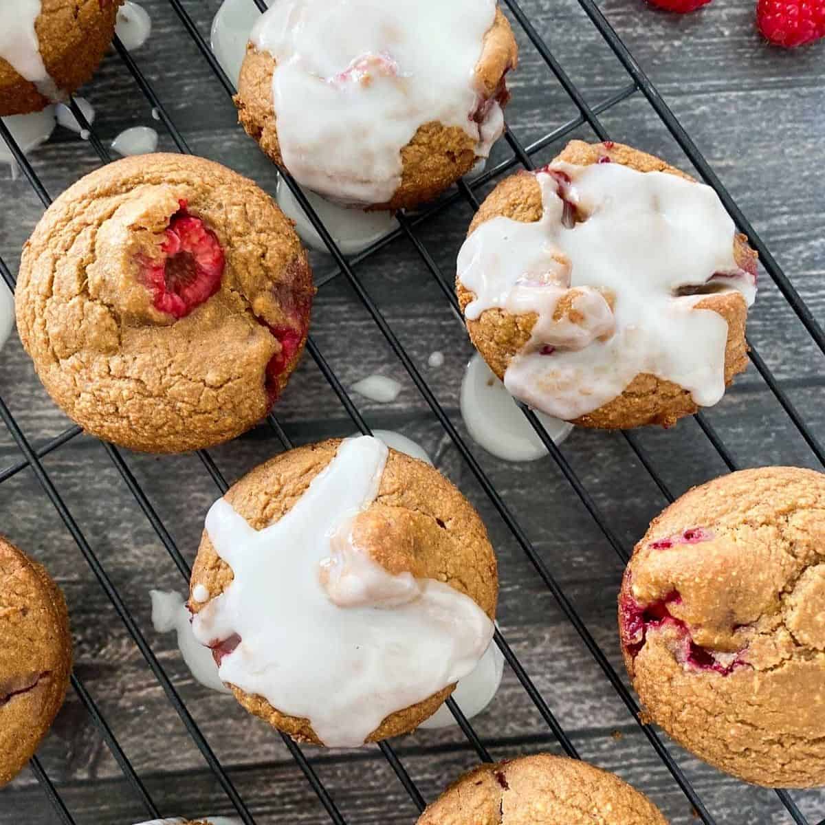 vegan raspberry muffins with white glaze on cooling rack