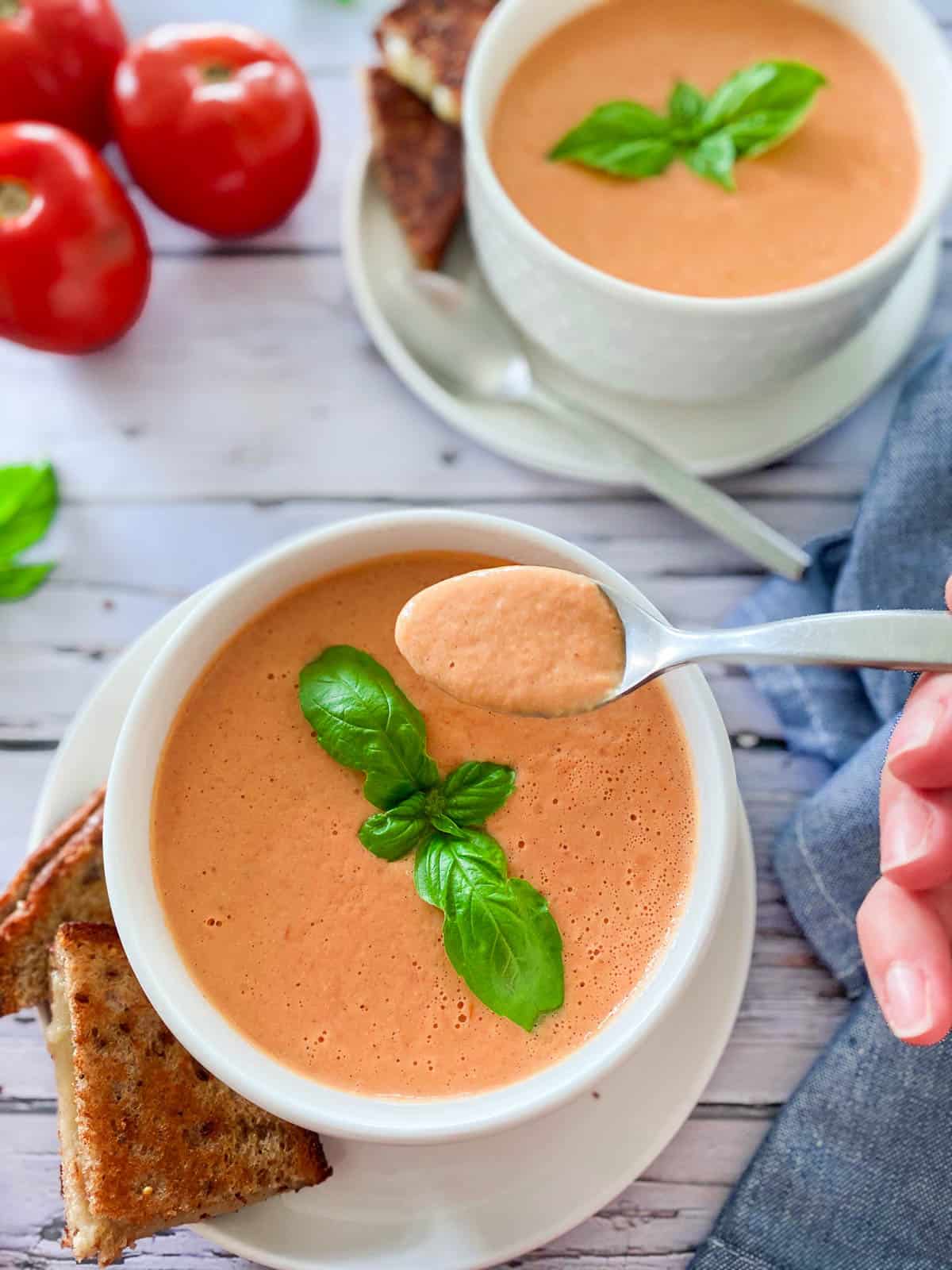 spoonful of vegan tomato bisque held over bowl of soup