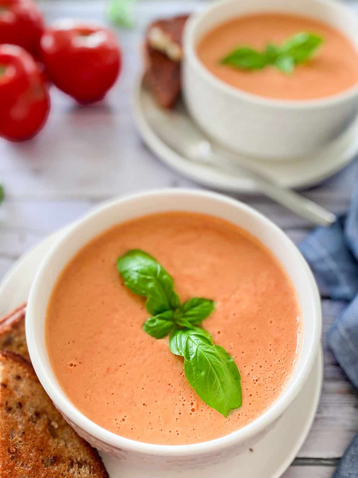 close up of bowl of vegan tomato bisque with basil garnish in center of bowl