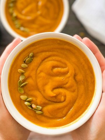 hands holding up bowl of pumpkin sweet potato soup