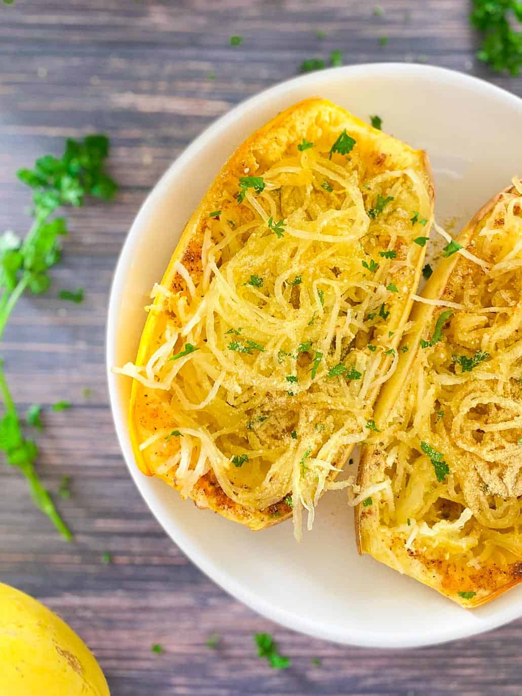 Spaghetti squash cut in half with noodles fluffed up and parsley garnish.
