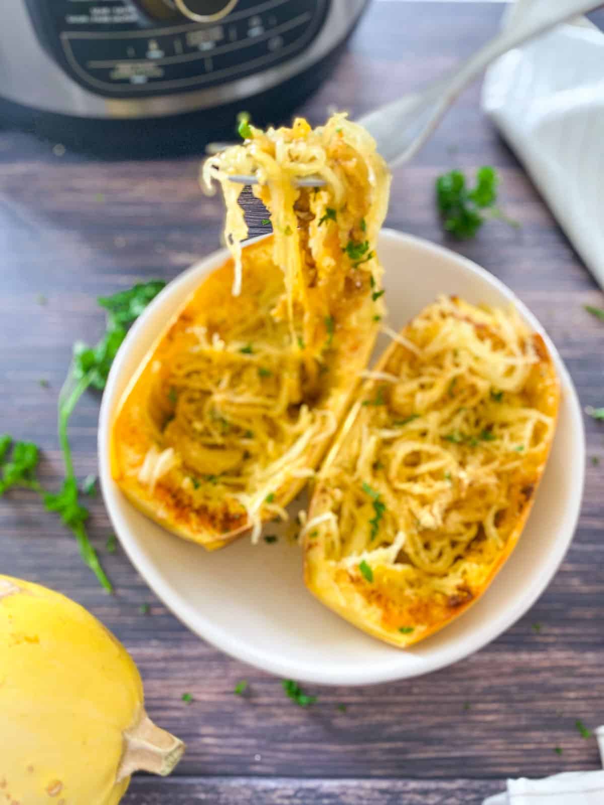 fork full of spaghetti squash being lifted from bowl of two halved squash.