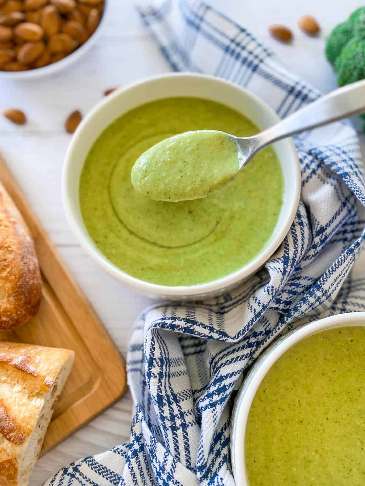 bowl of creamy broccoli soup with spoon lifting up a bite full from the bowl.