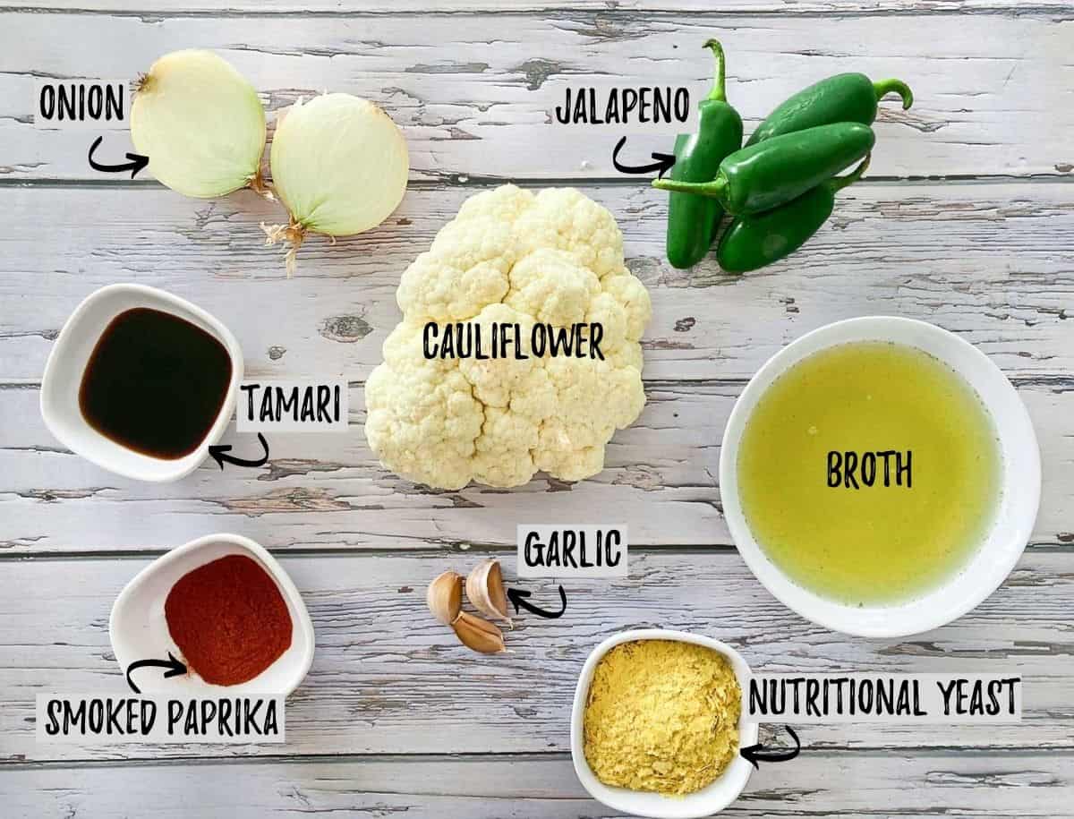 Ingredients to make vegan cauliflower cheese sauce scattered across grey deck.