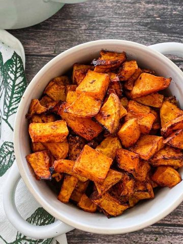 Two bowls with handles filled with air fried butternut squash,