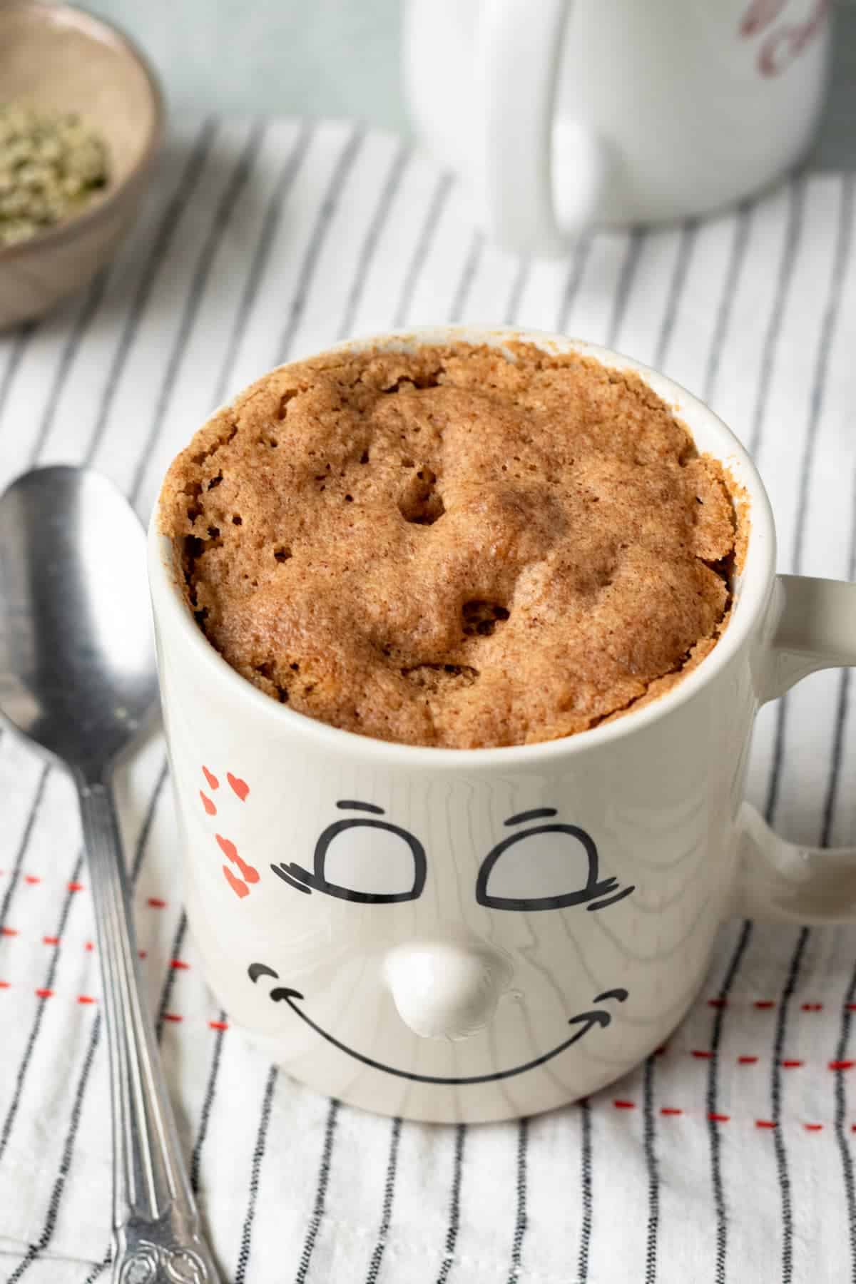 Mug with microwaved muffin inside and spoon on the side.
