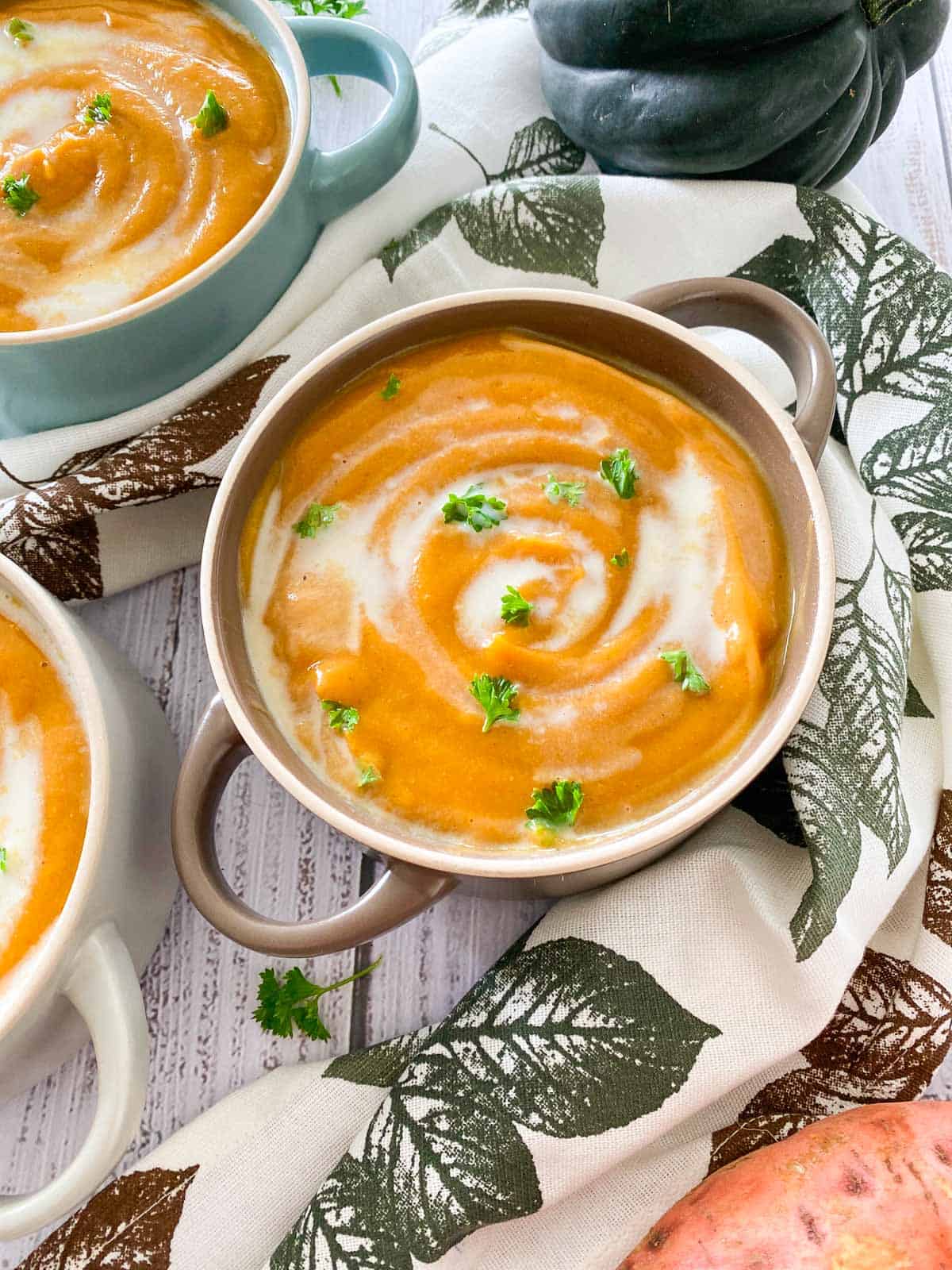 Close up of bowl of sweet potato soup with cream and parsley garnish.