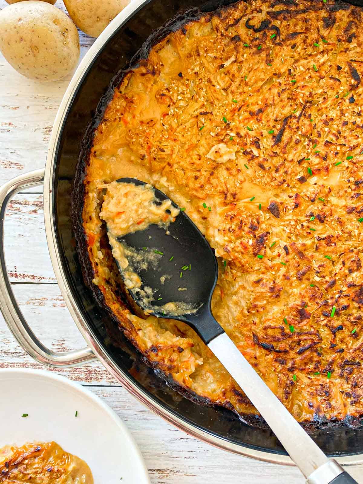 Hash brown casserole in round dish with ladle sitting inside.