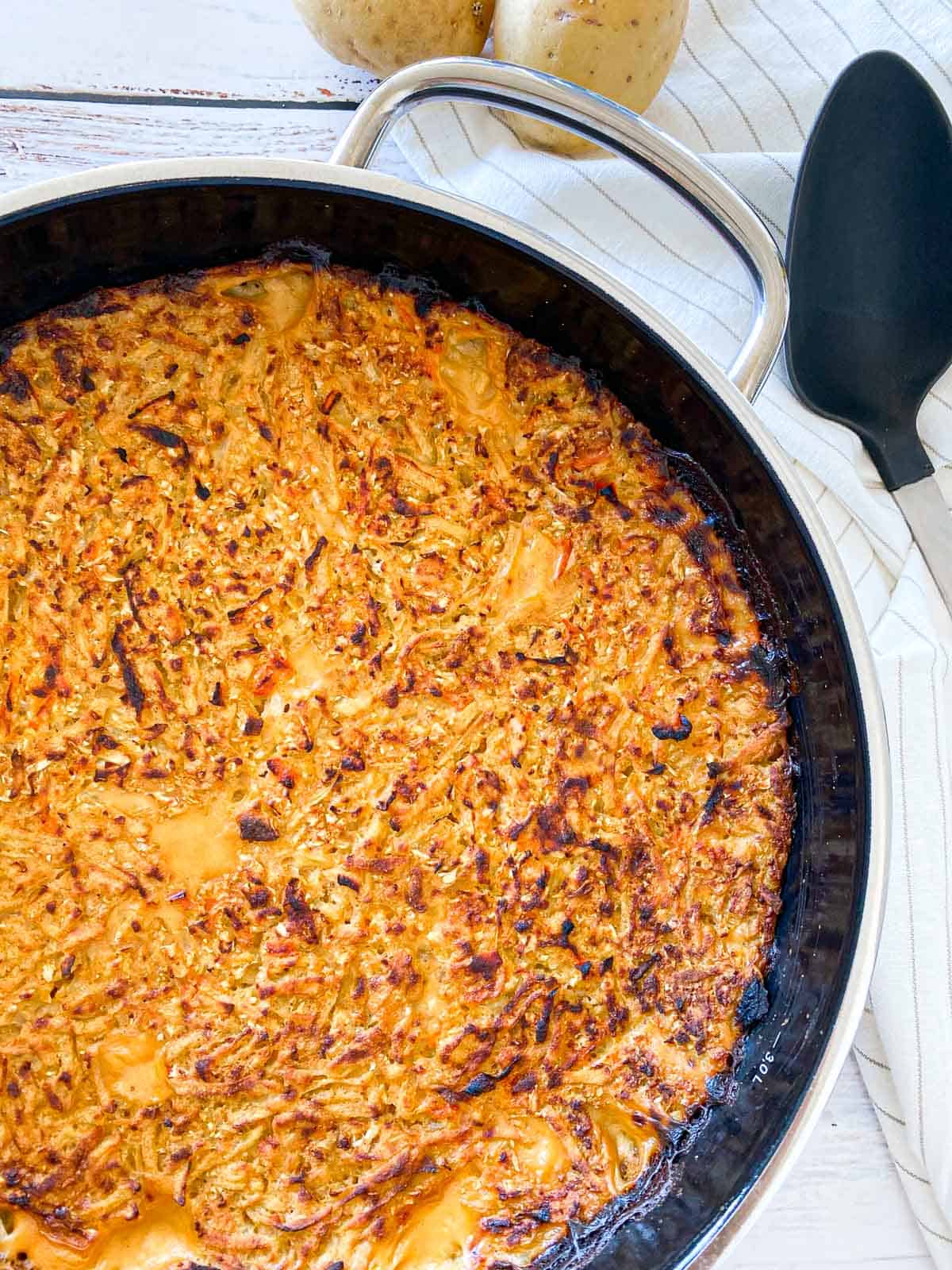 Round casserole dish filled with vegan cheesy shredded potatoes.