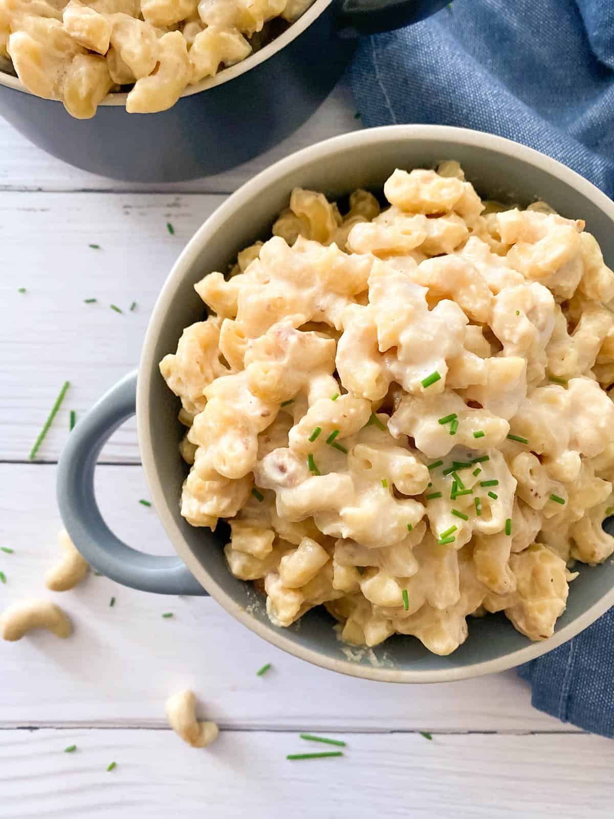vegan mac and cheese in blue bowl with chives garnished on top.