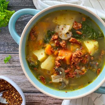 Bowl of soup with potatoes, kale, carrots and vegan bacon.