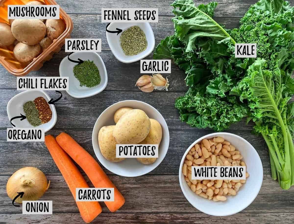 Ingredients needed to make vegan zuppa toscana scattered on grey deck.