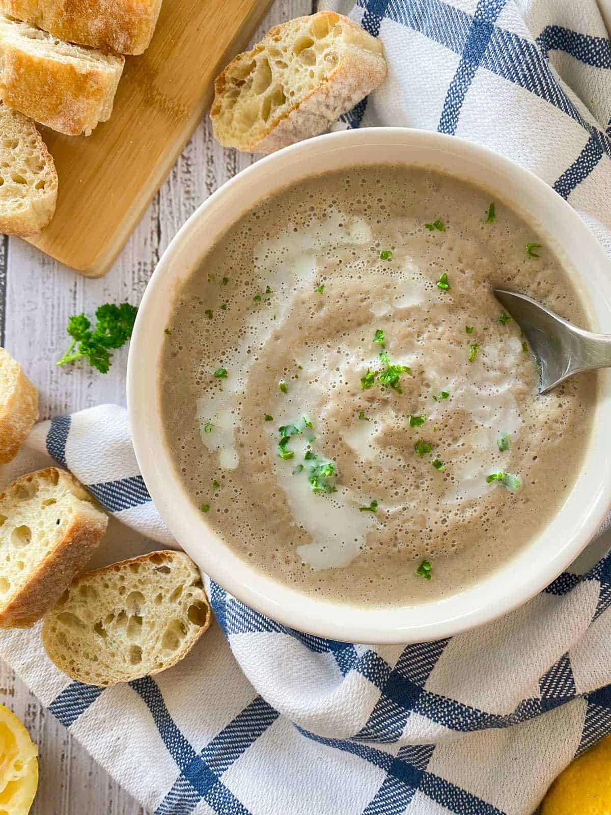 Bowl of mushroom soup with spoon held inside, about to scoop a bite.
