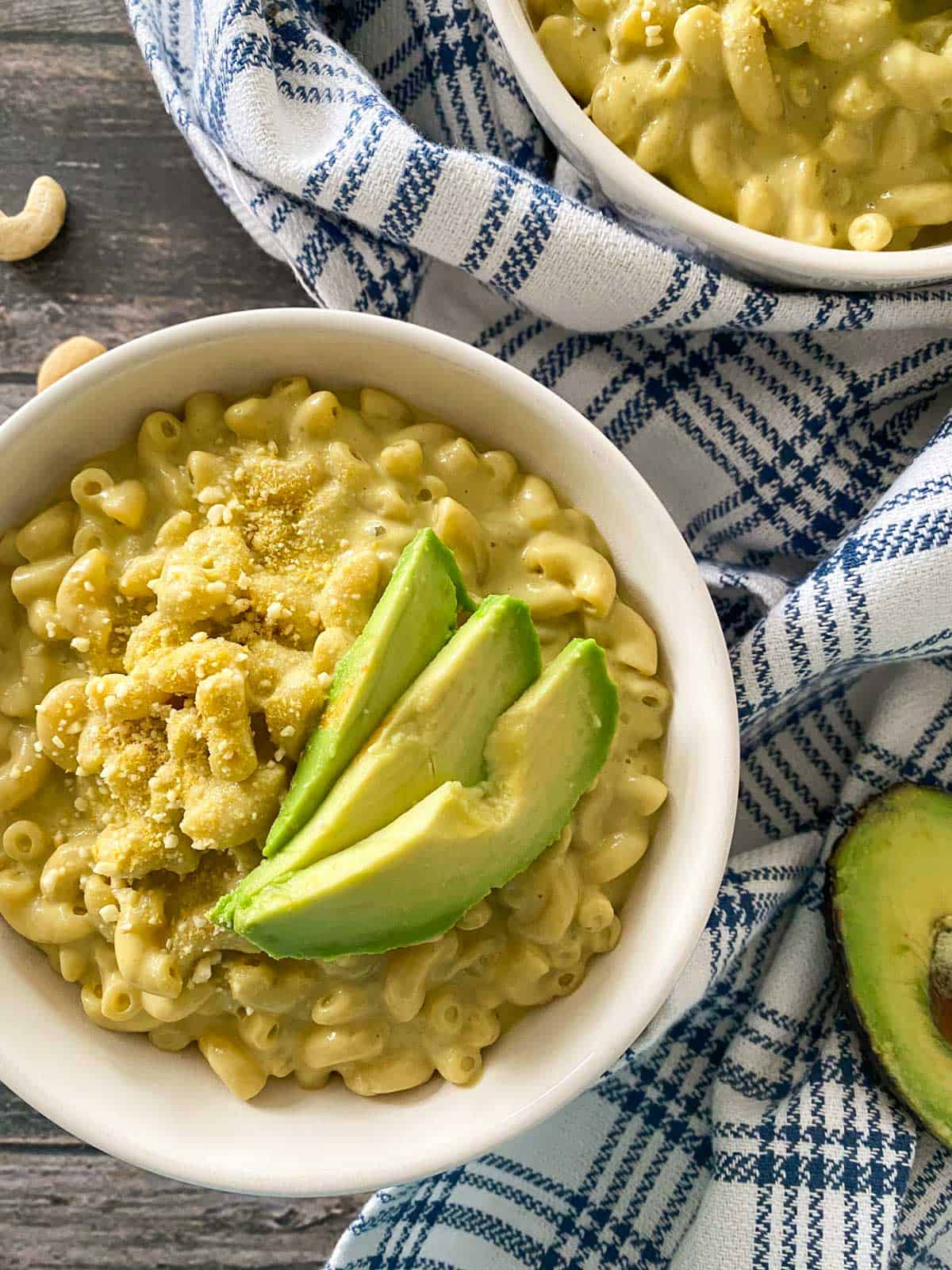 Mac and cheese in bowl with avocado slices on top.