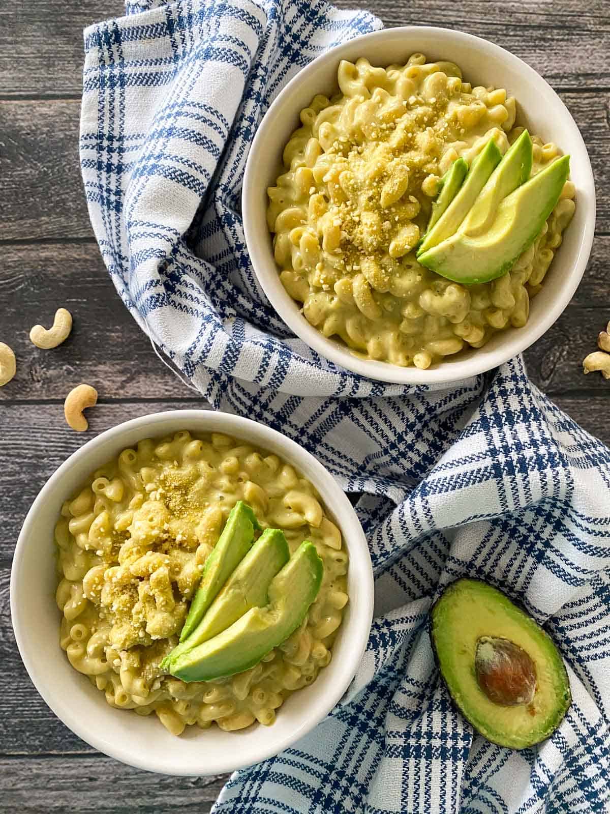 Two bowls of mac and cheese with avocado slices on top.