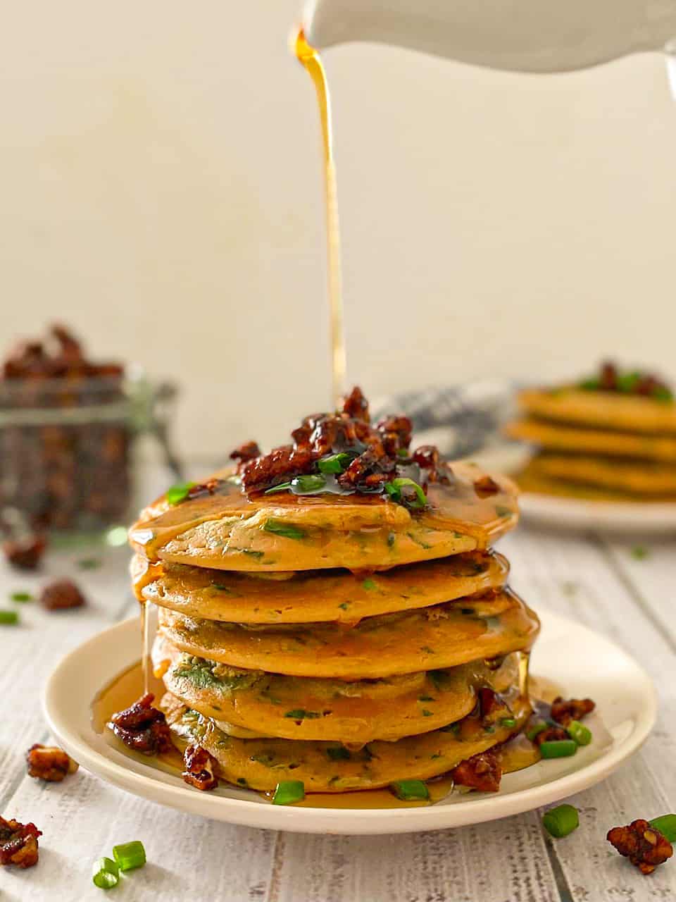 Savoury pancake stack with bacon and onion on top.