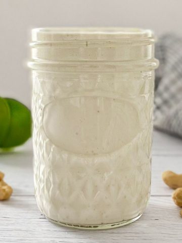 Jar filled with vegan crema fresca with limes in the background.
