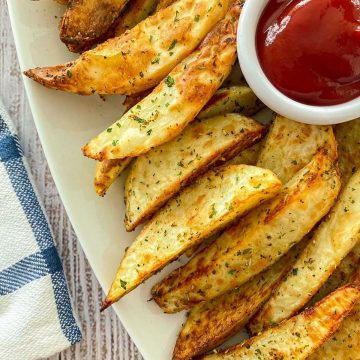 potato wedges in white serving dish with bowl of ketchup.