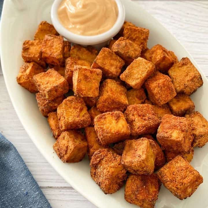 air fryer tofu on white serving dish with dipping sauce.