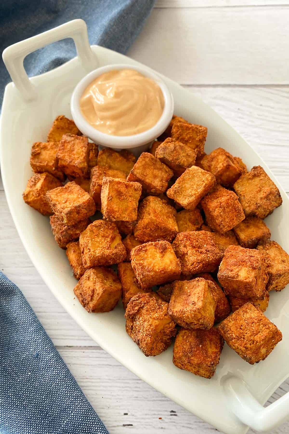 air fryer tofu on white serving dish with dipping sauce.