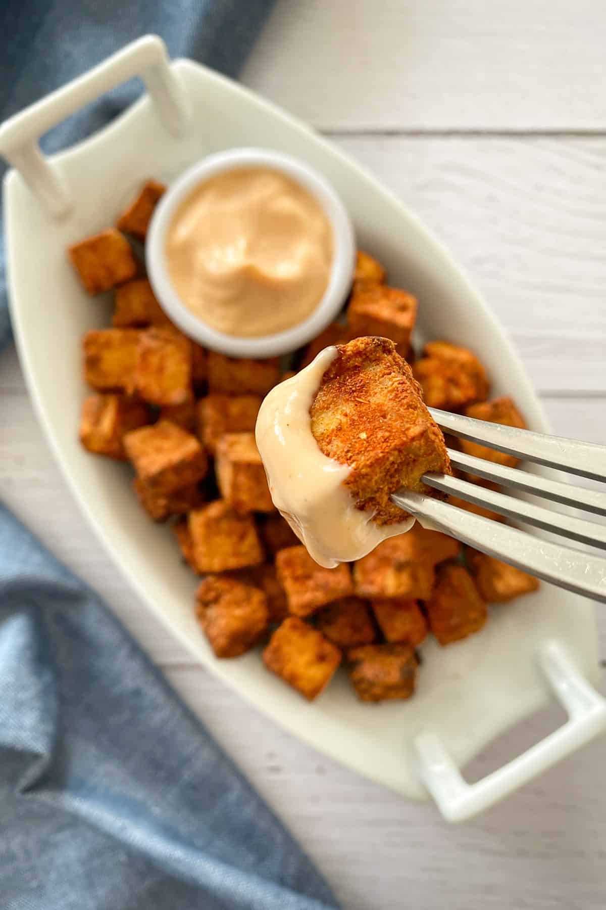 Fork with cubed tofu on it that has been dunked into a pink dip.