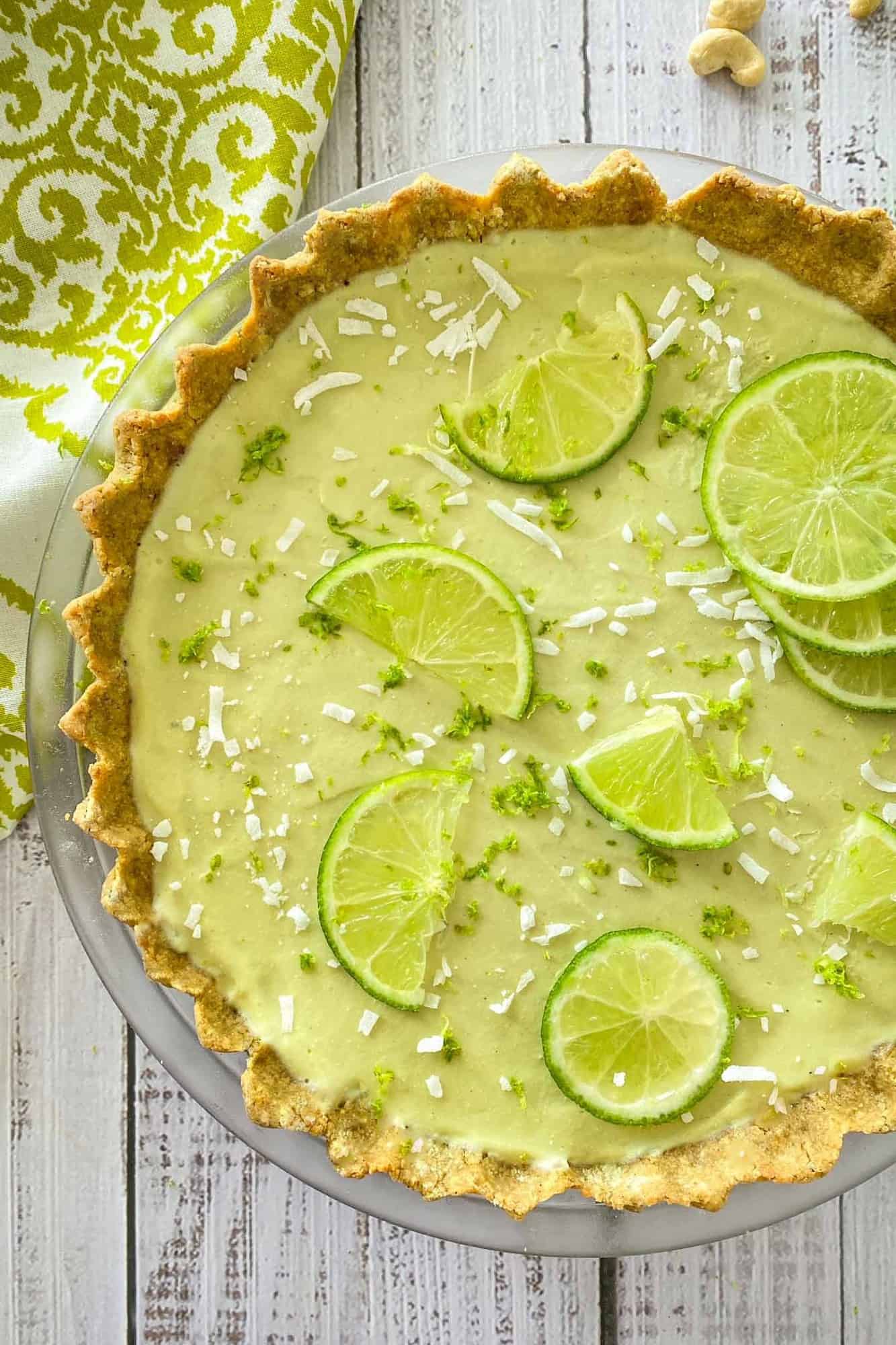 Overhead view of key lime pie with lime zest and coconut shreds on top.