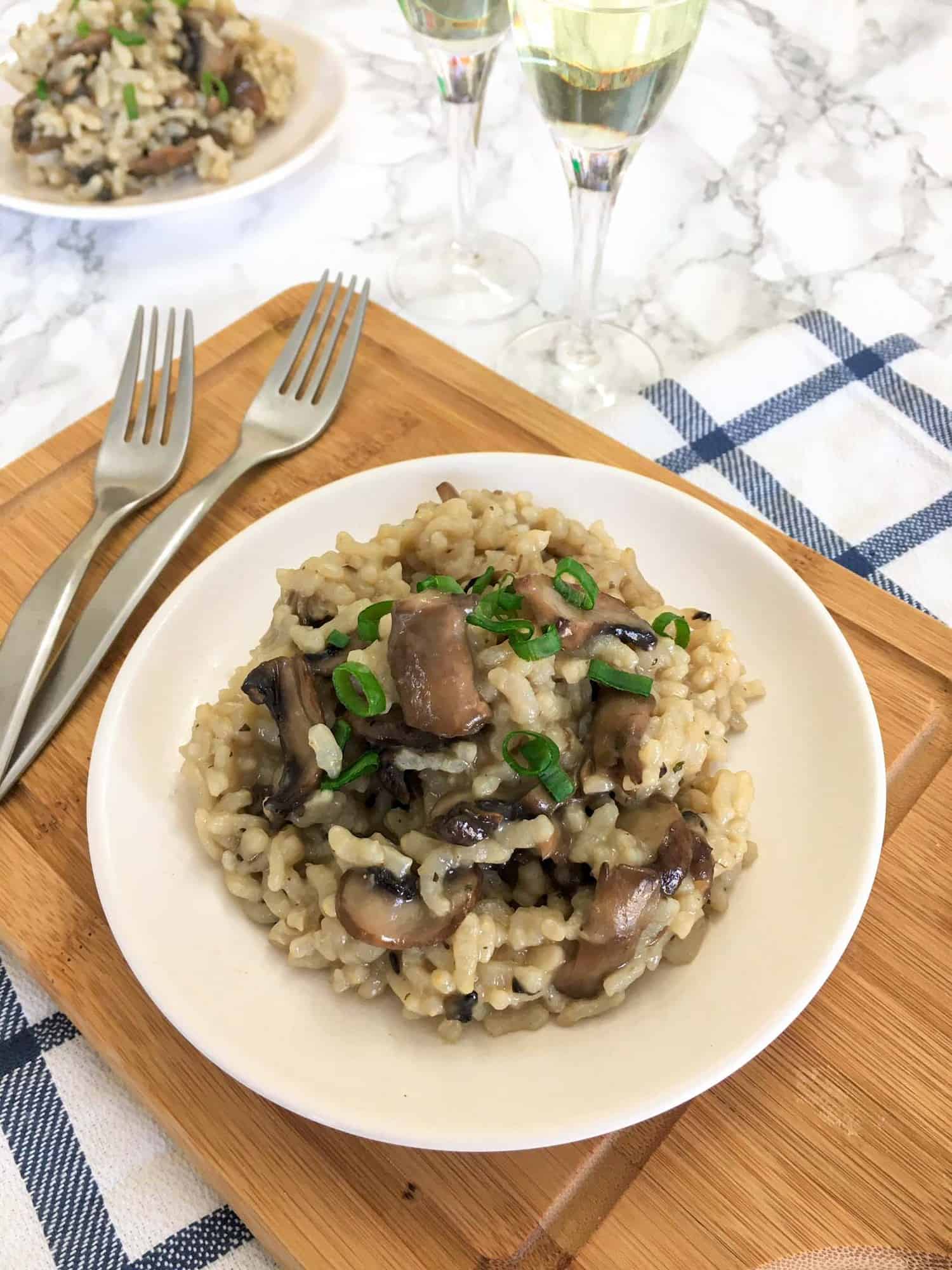 Mushroom risotto in white plate with green onion garnish.