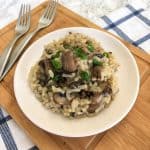 Mushroom risotto in white plate with green onion garnish.