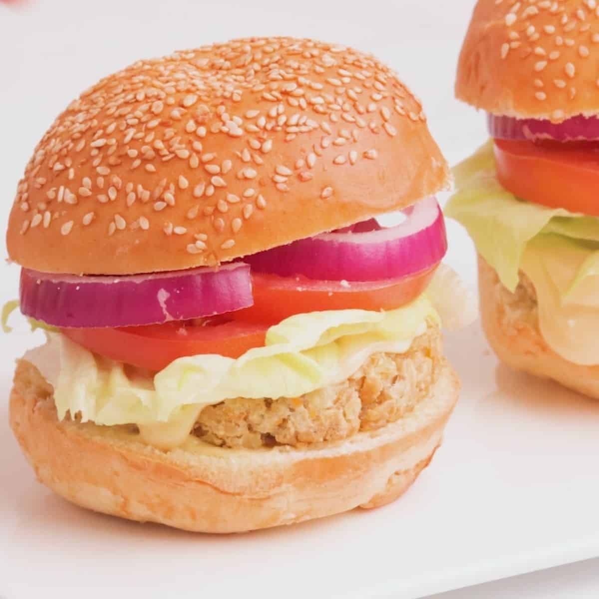 Vegan chicken burger in bun with onion, tomato, lettuce and mayo.
