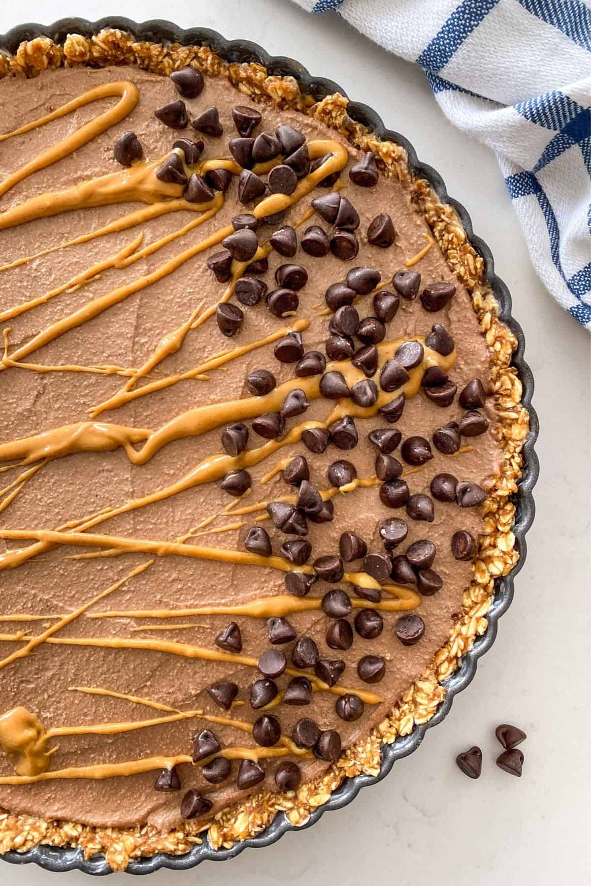 Close up of peanut butter pie with peanut butter drizzle and chocolate chips on top.