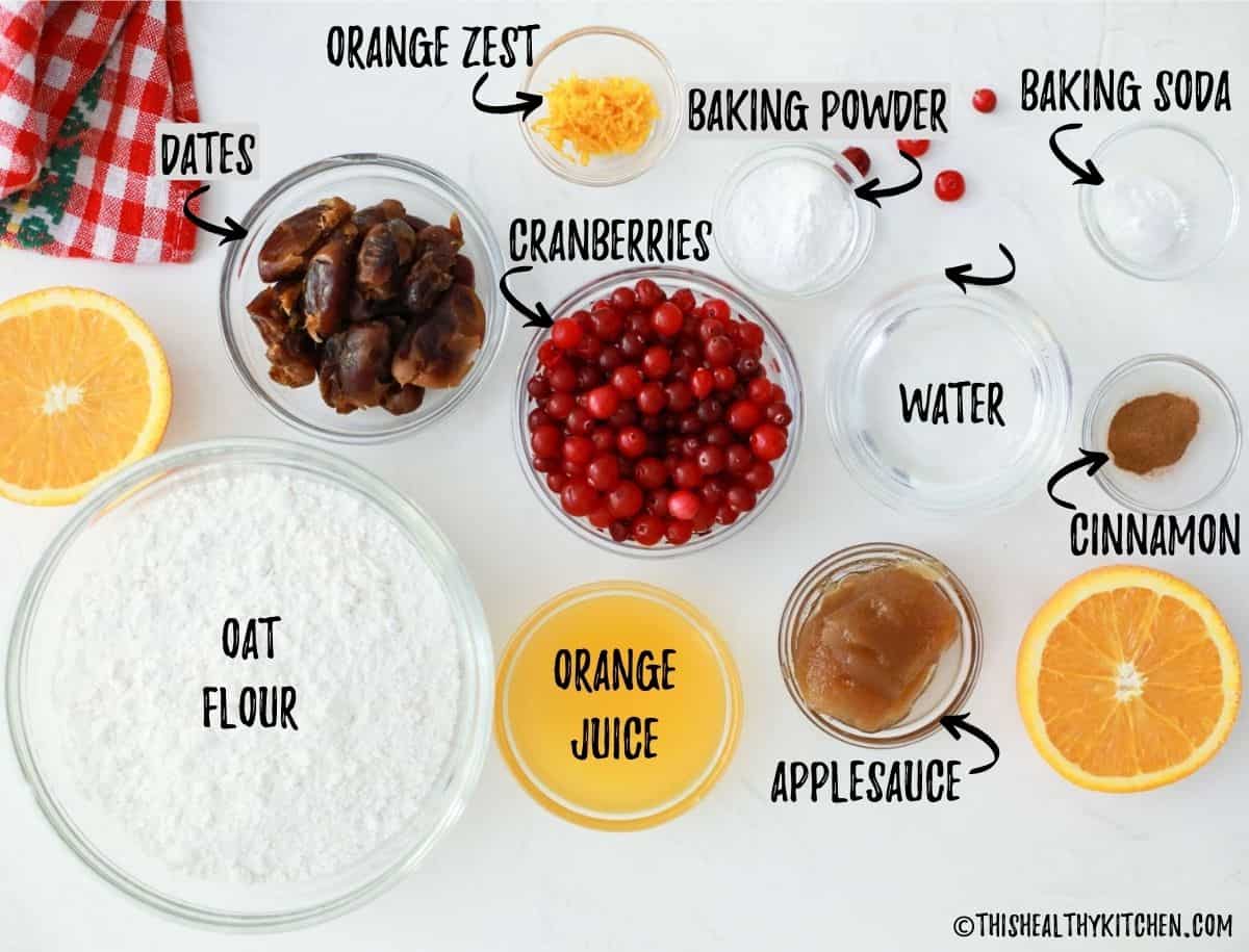 Ingredients needed to make cranberry orange bread scattered on kitchen countertop.