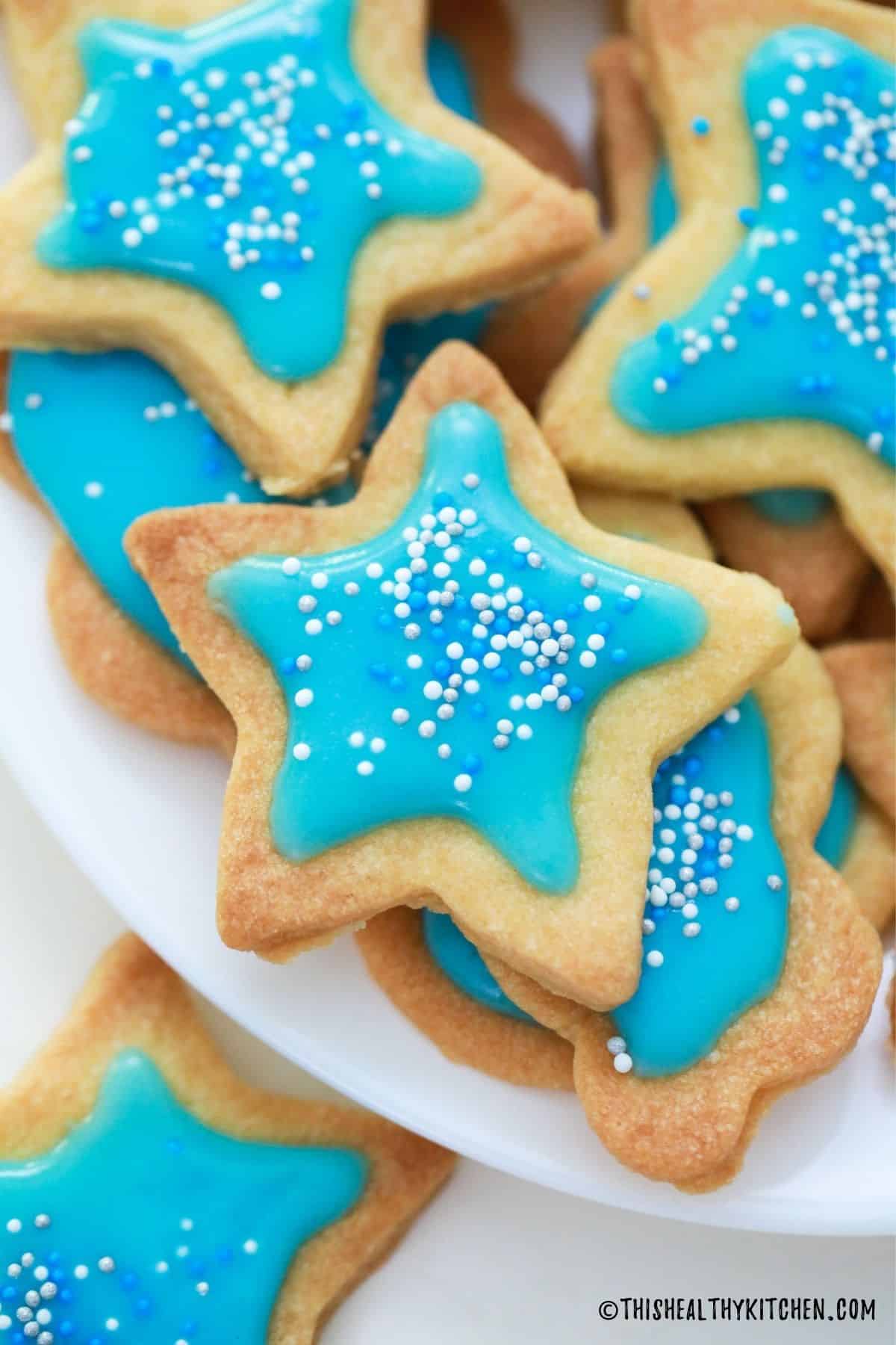 Close up of star shaped cookie with blue icing and sprinkles on top.