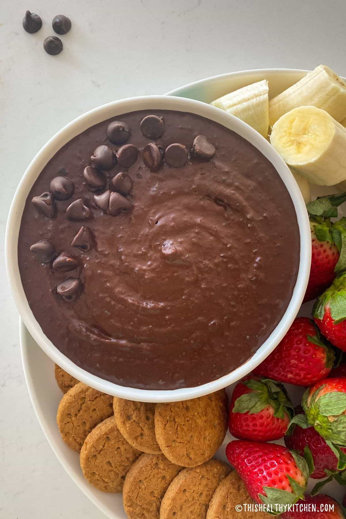 White bowl filled with chocolate hummus and chocolate chips on top.