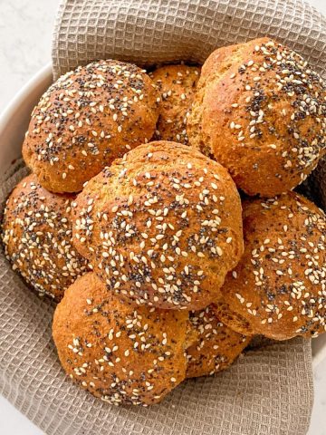 Basket filled with hamburger buns with seeds on top.