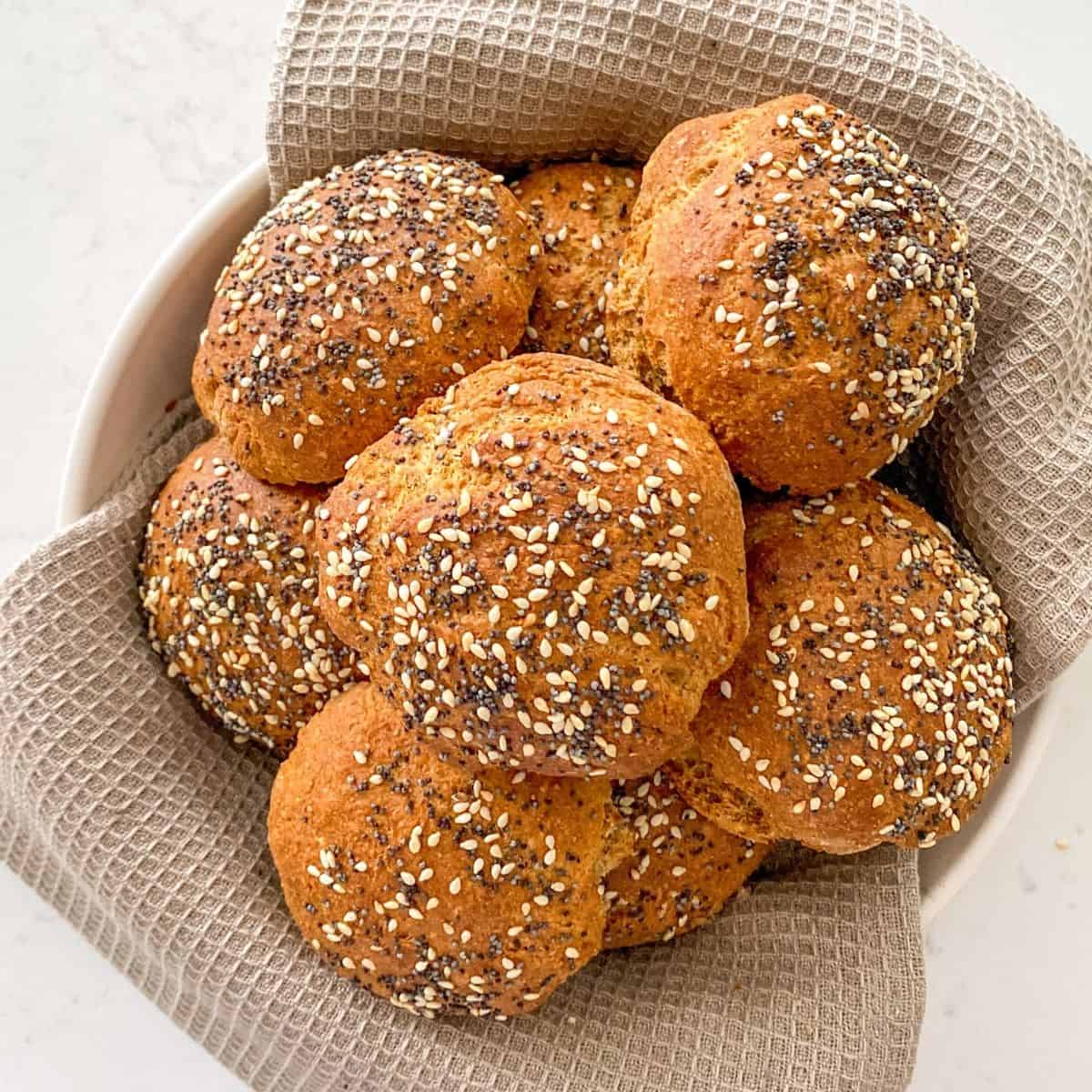 Basket filled with hamburger buns with seeds on top.