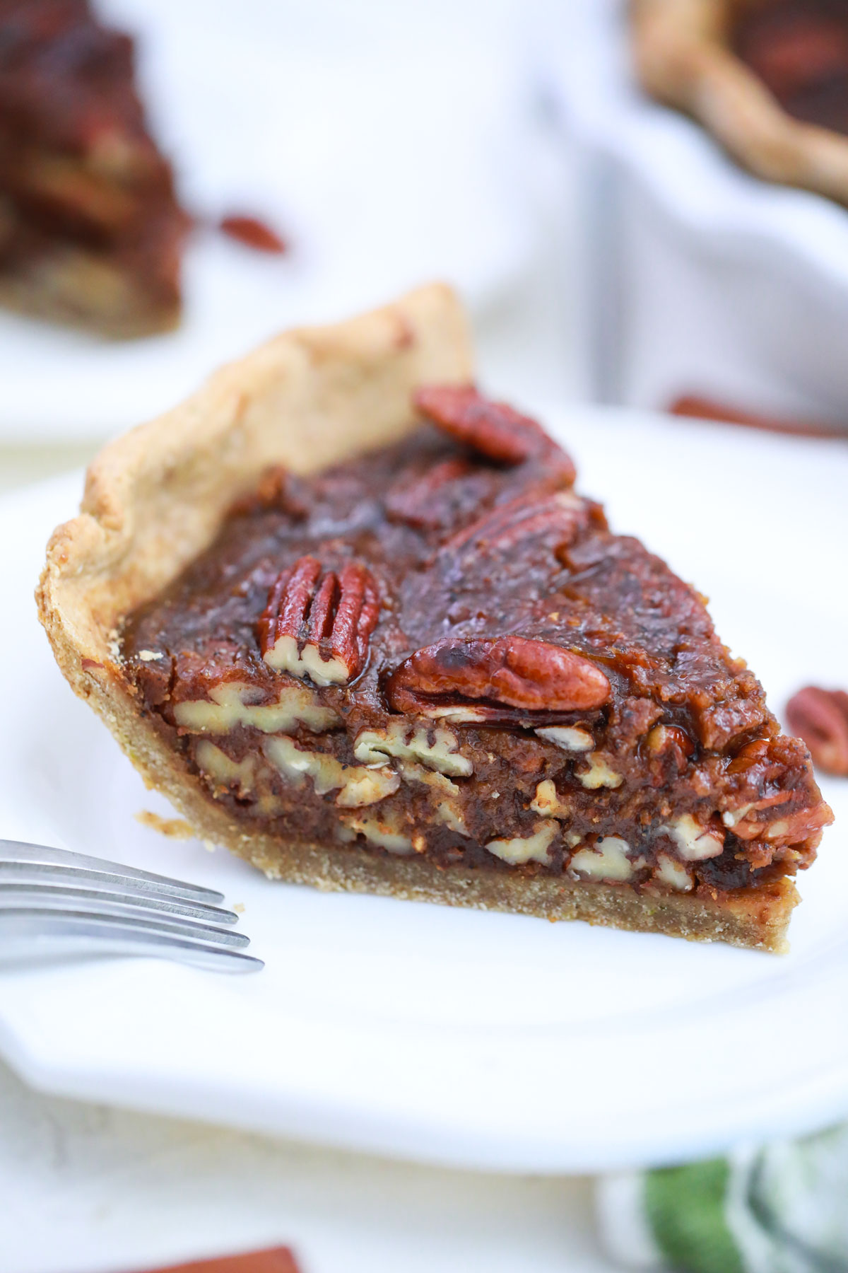 Side view of slice of pecan pie in white plate.