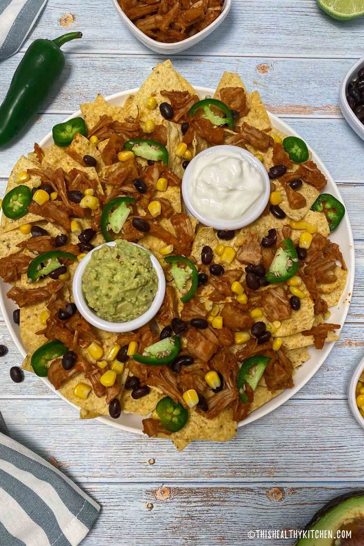 Platter of nachos with guacamole and sour cream for dipping.