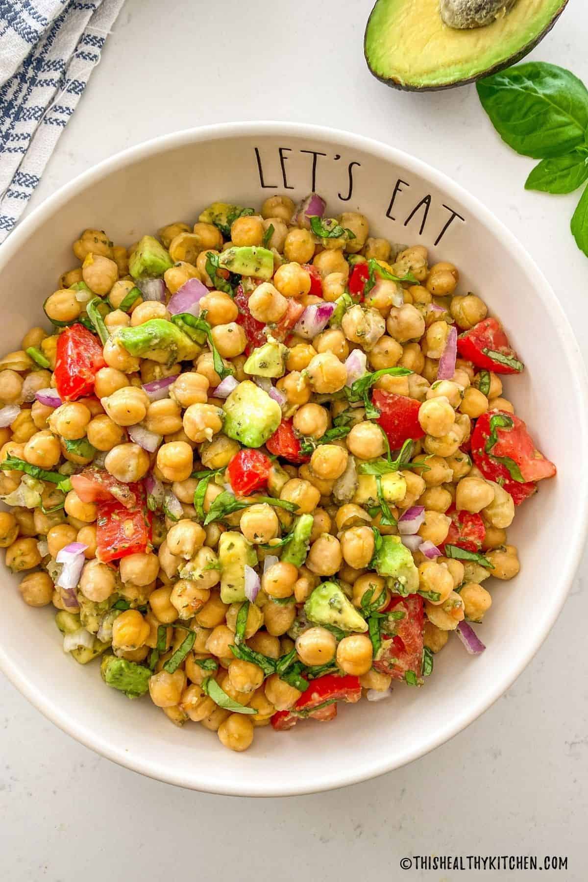 Chickpea, avocado and tomato salad in white serving bowl.