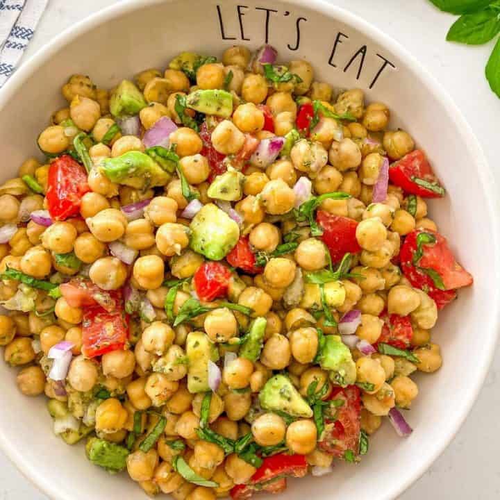 Chickpea avocado and tomato salad in white serving bowl.