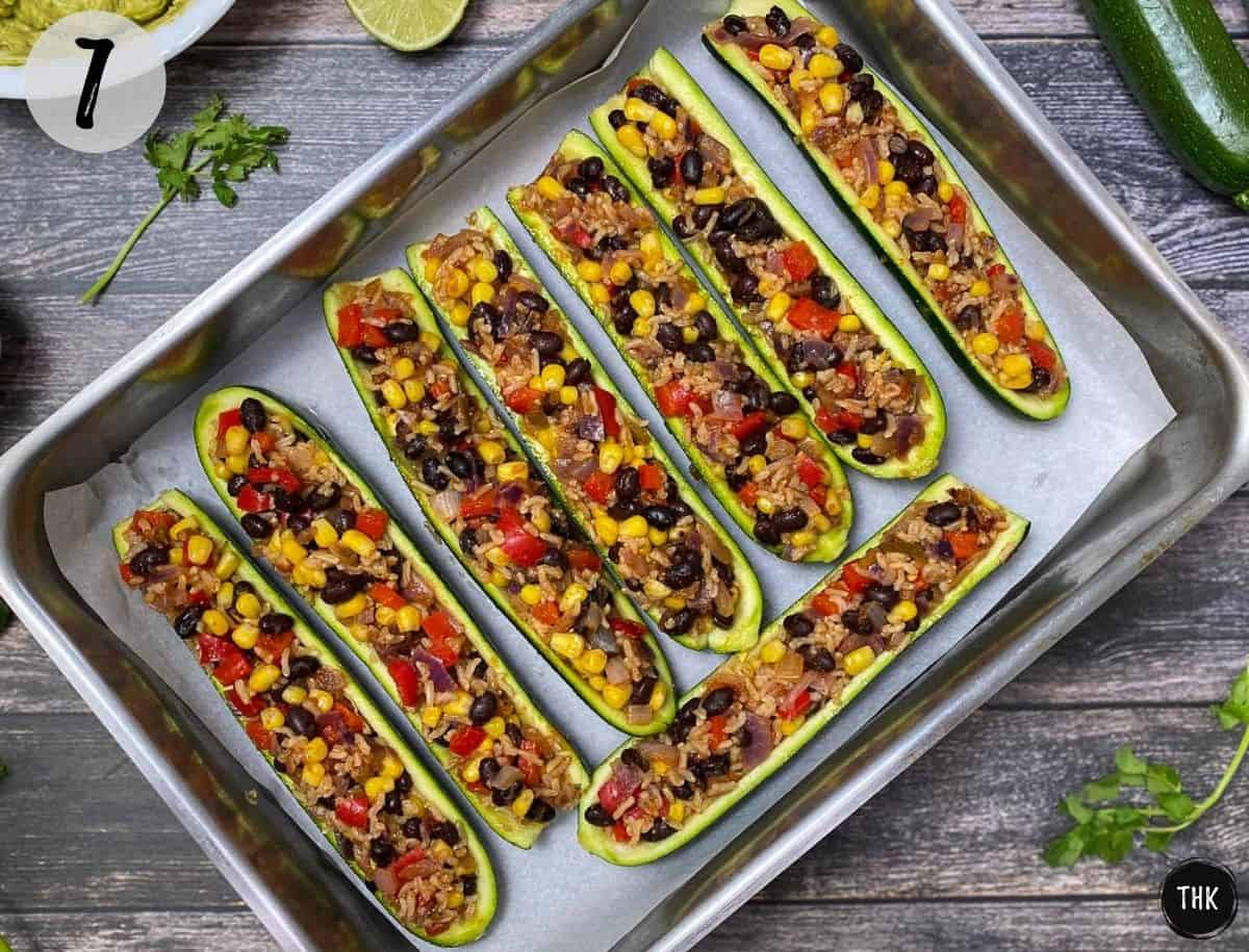 Baked zucchini burrito boats inside baking tray.
