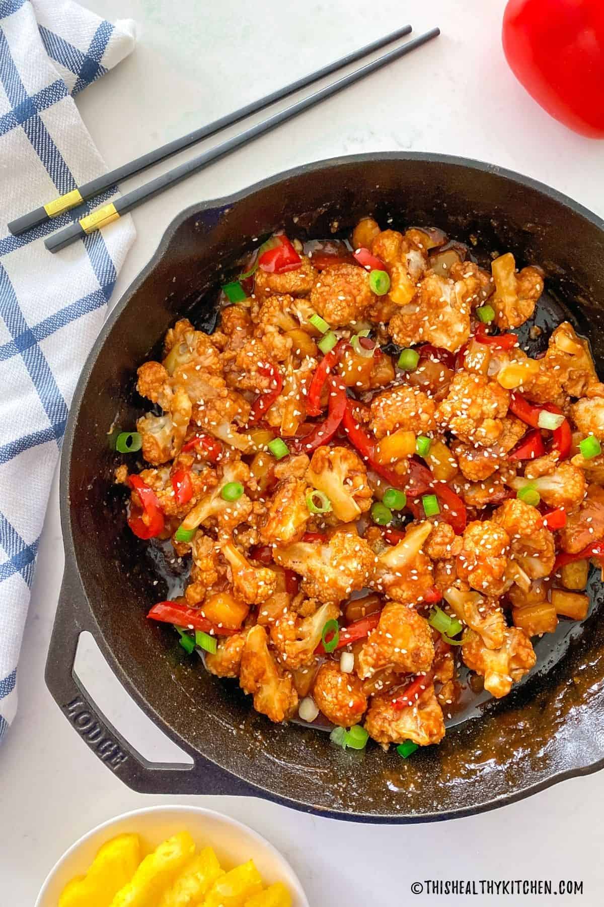 Cast iron pan with sweet and sour cauliflower inside.