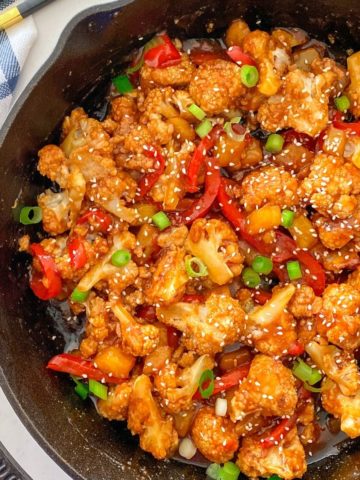 Cauliflower with peppers and sweet and sour sauce in cast iron pan.