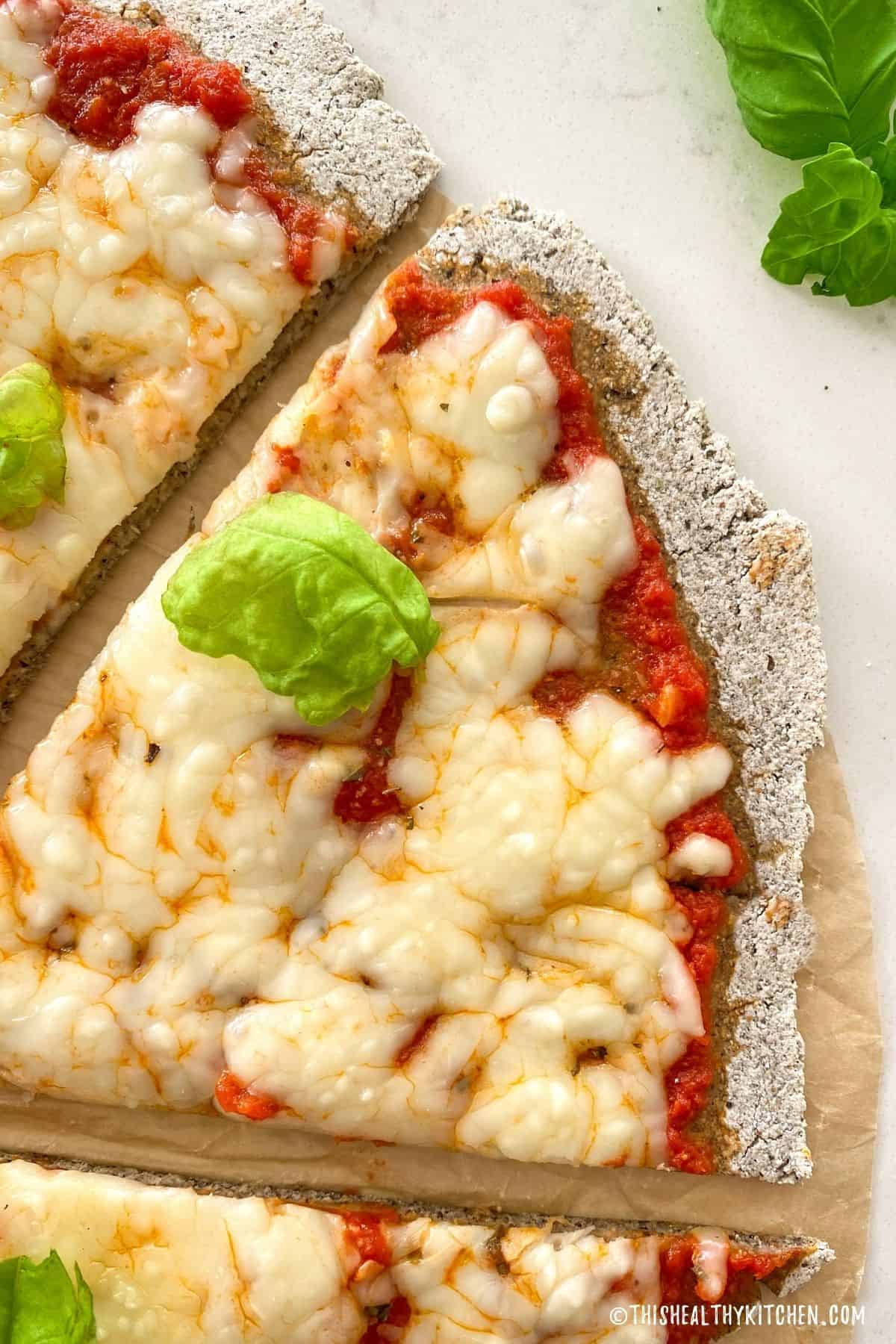 Close up of a slice of pizza with cheese and basil on top.