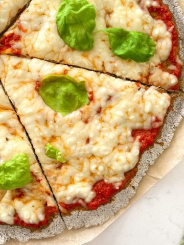 Buckwheat pizza with tomato sauce, cheese and basil on top.
