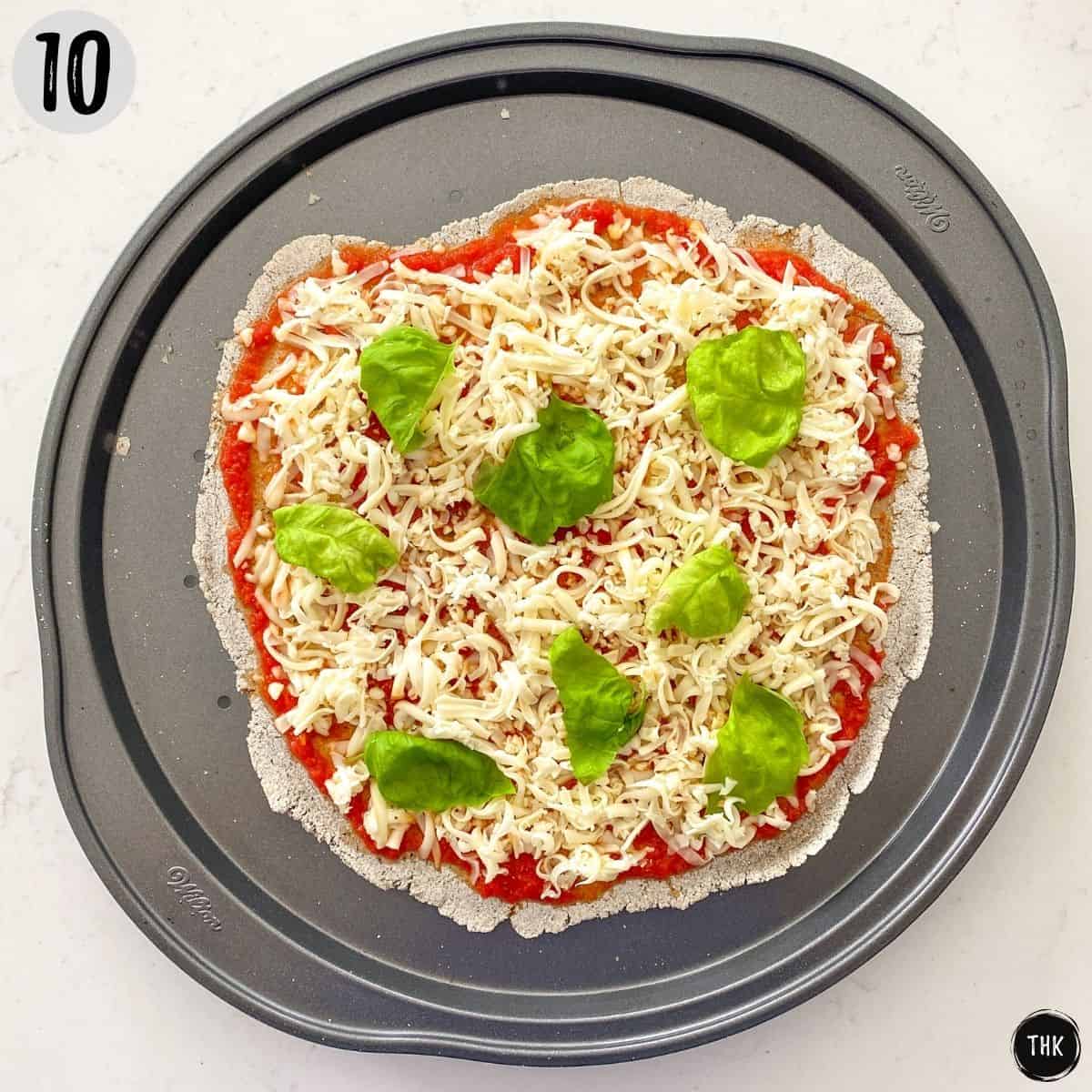 Pizza with cheese and basil on top before baking.
