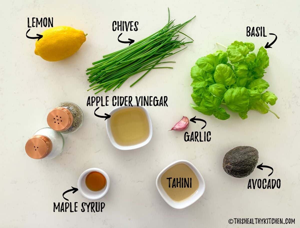Lemon, chives, basil, vinegar, garlic, avocado and tahini on kitchen counter top.