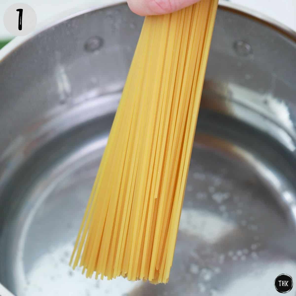 Spaghetti being placed in pot of boiling water.